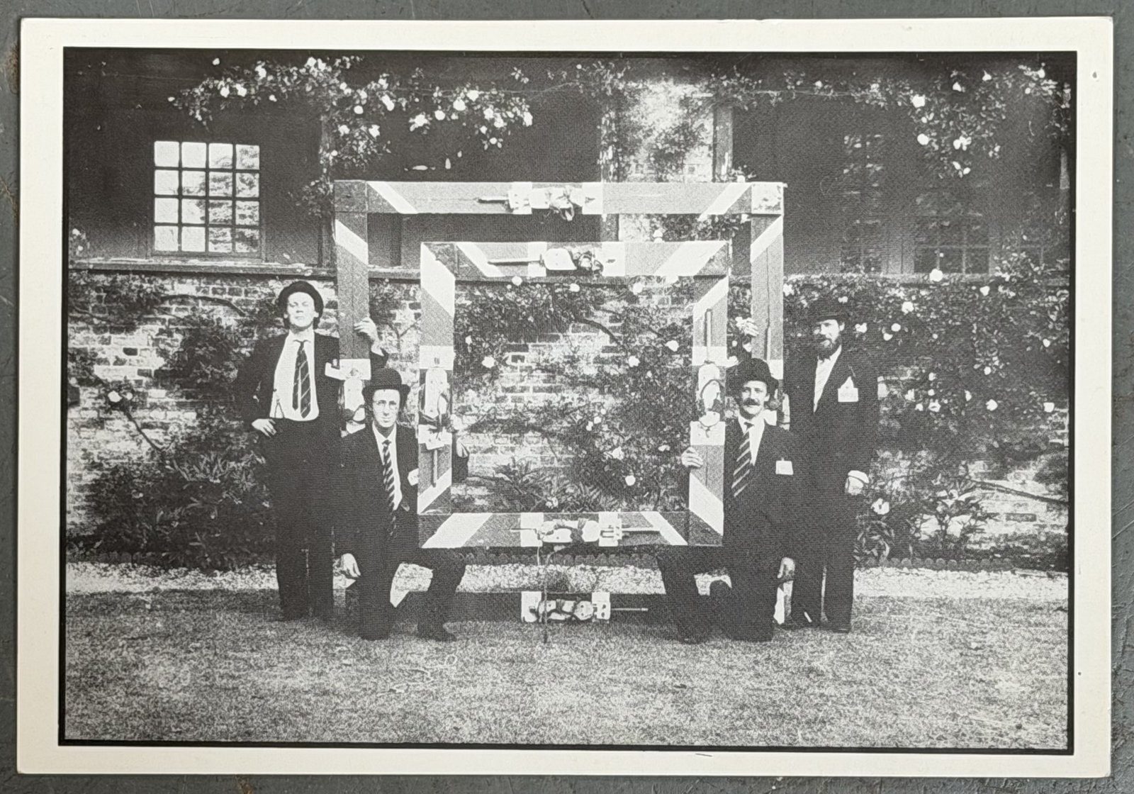 The Great British Square Dancers — bowler-hatted performers around a woven timber frame in a garden